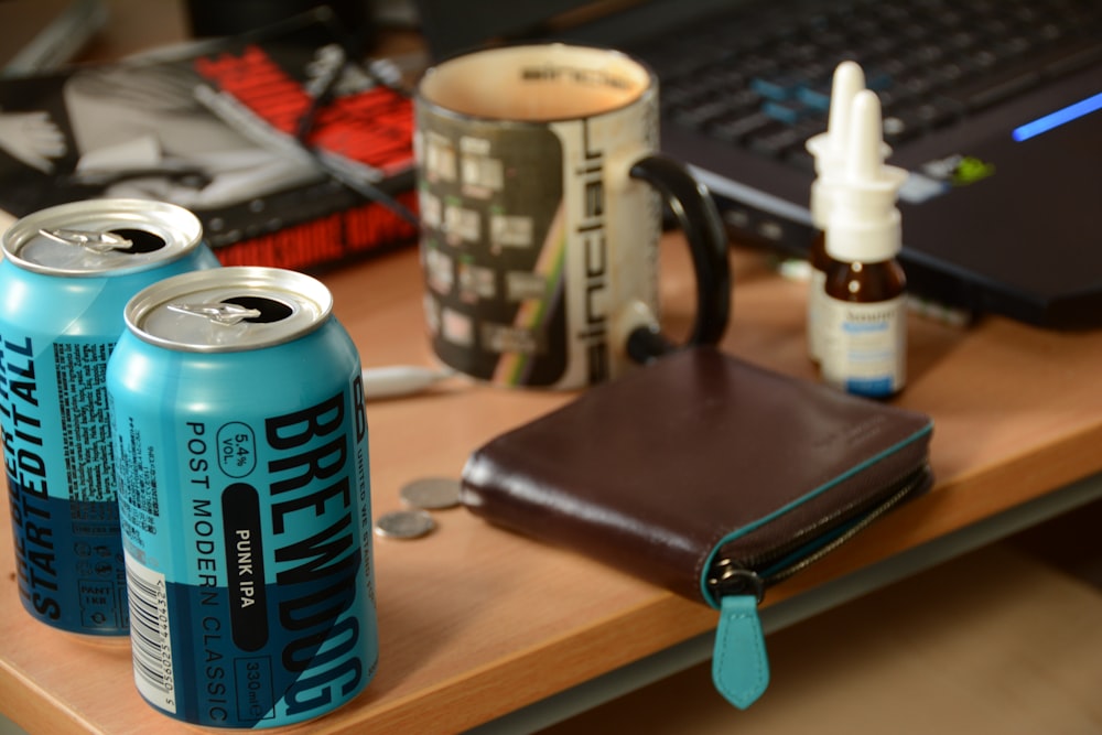 blue can beside black leather wallet on brown wooden table