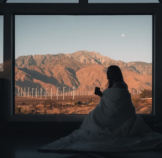 Woman in home looking at desert wind energy system