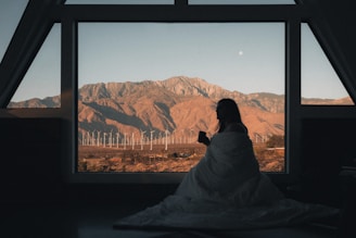 Woman in home looking at desert wind energy system