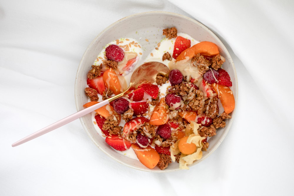 white ceramic bowl with cereal and sliced strawberries