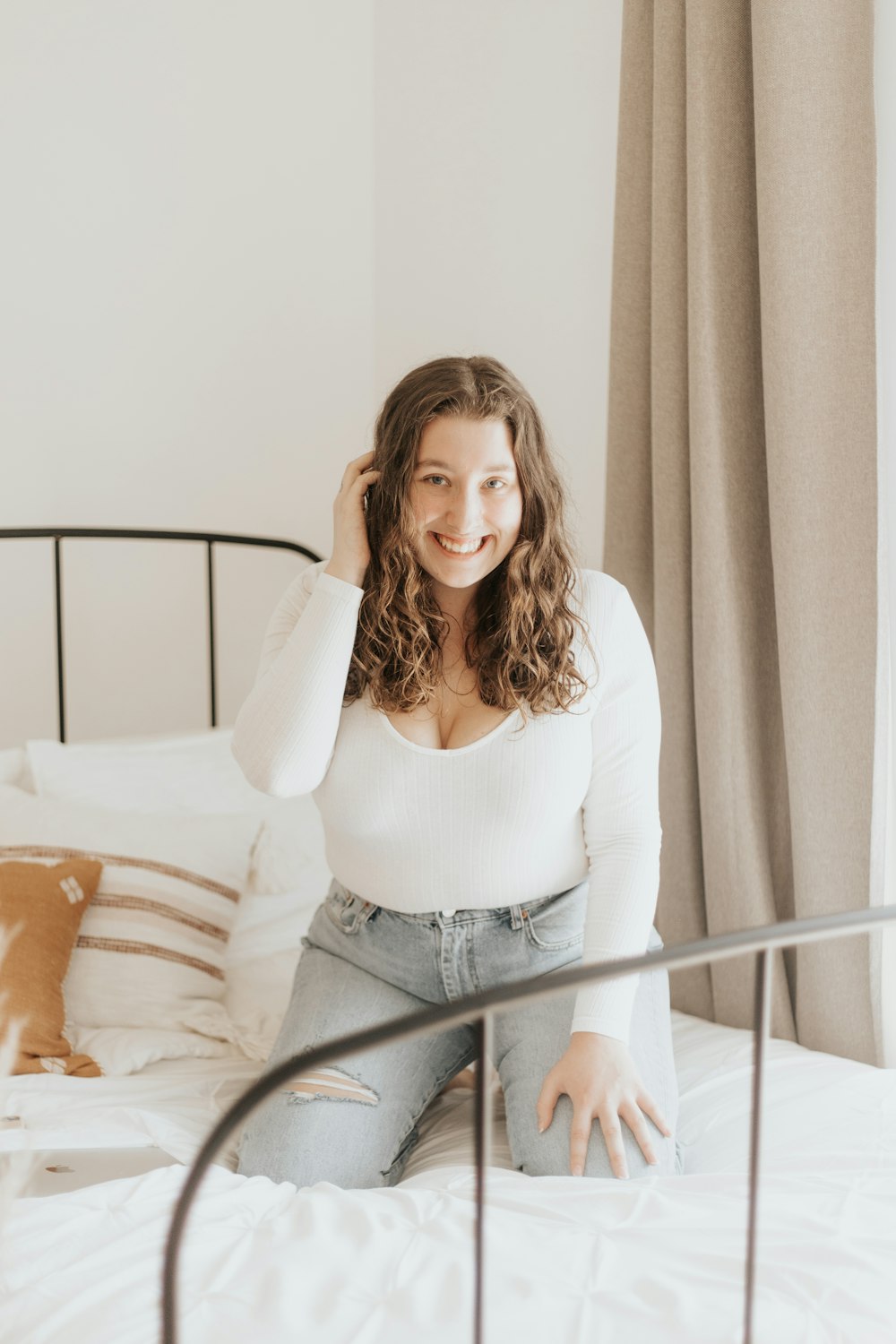 woman in white long sleeve shirt and blue denim jeans sitting on bed