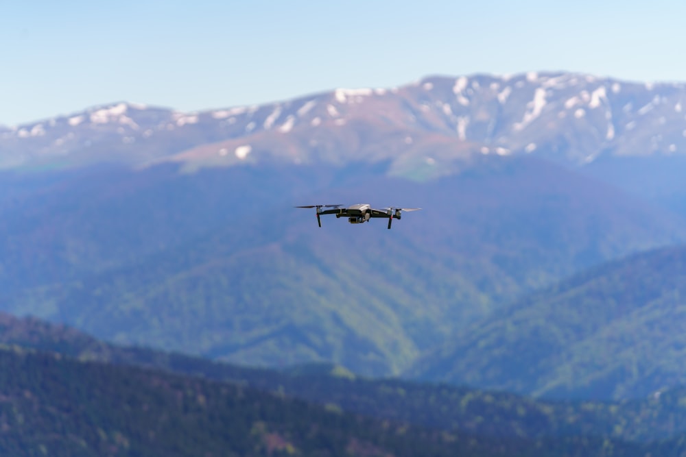 Schwarzer Hubschrauber, der tagsüber über grüne Berge fliegt