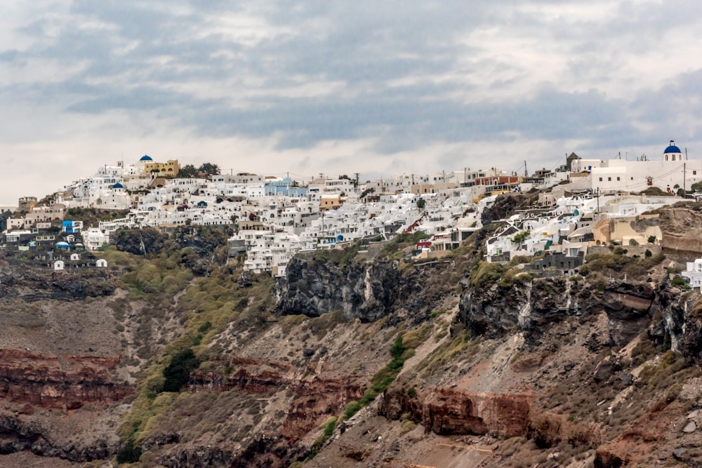 white concrete buildings on mountain under white clouds during daytime