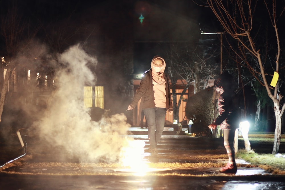 woman in black and white striped long sleeve shirt standing on road during nighttime