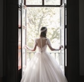 woman in white wedding dress standing near window during daytime