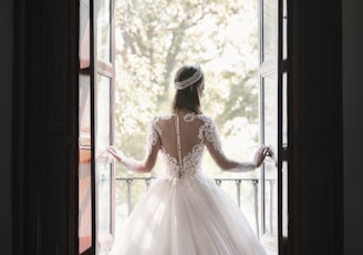 woman in white wedding dress standing near window during daytime