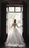 woman in white wedding dress standing near window during daytime
