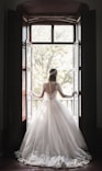 woman in white wedding dress standing near window during daytime