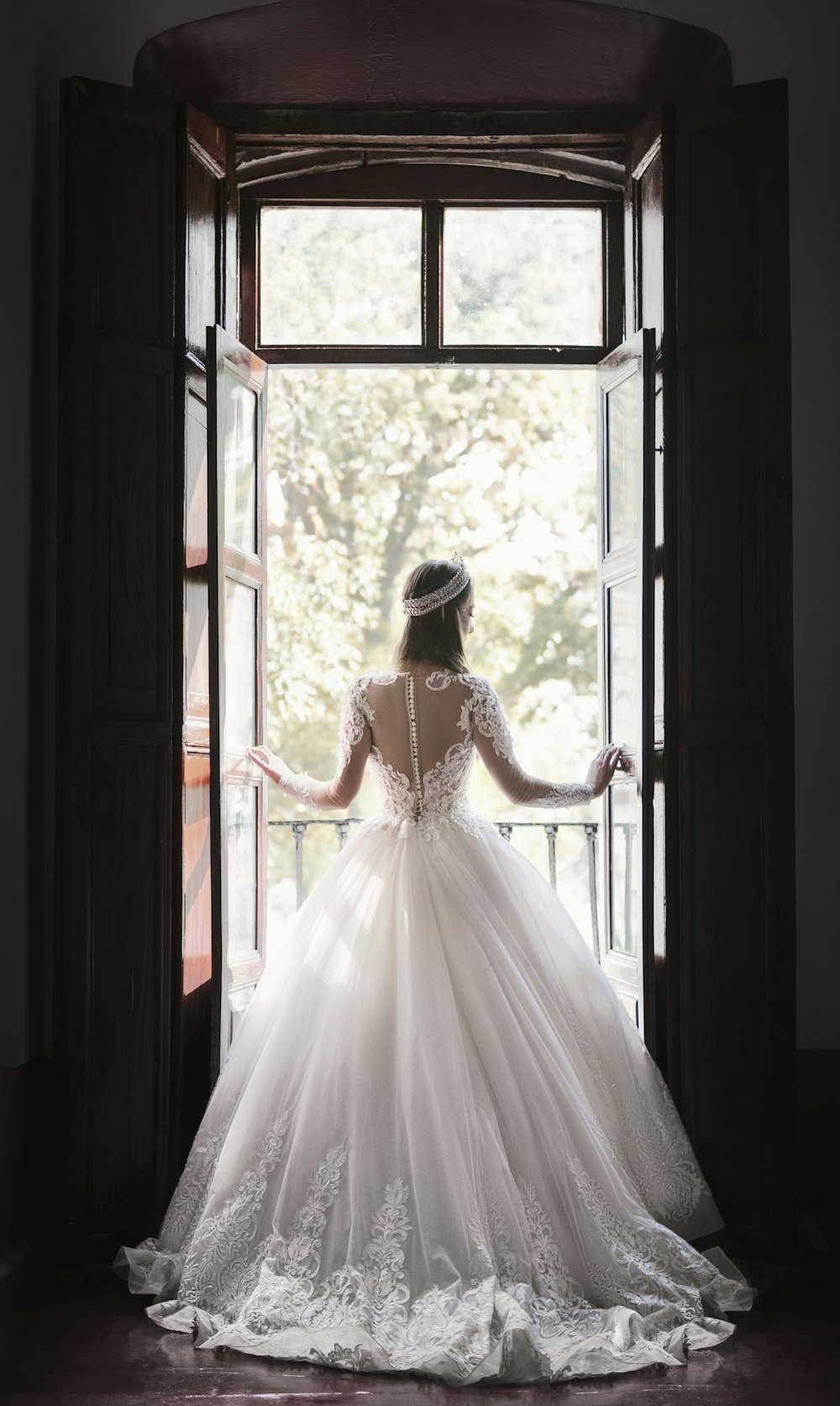 woman in white wedding dress standing near window during daytime