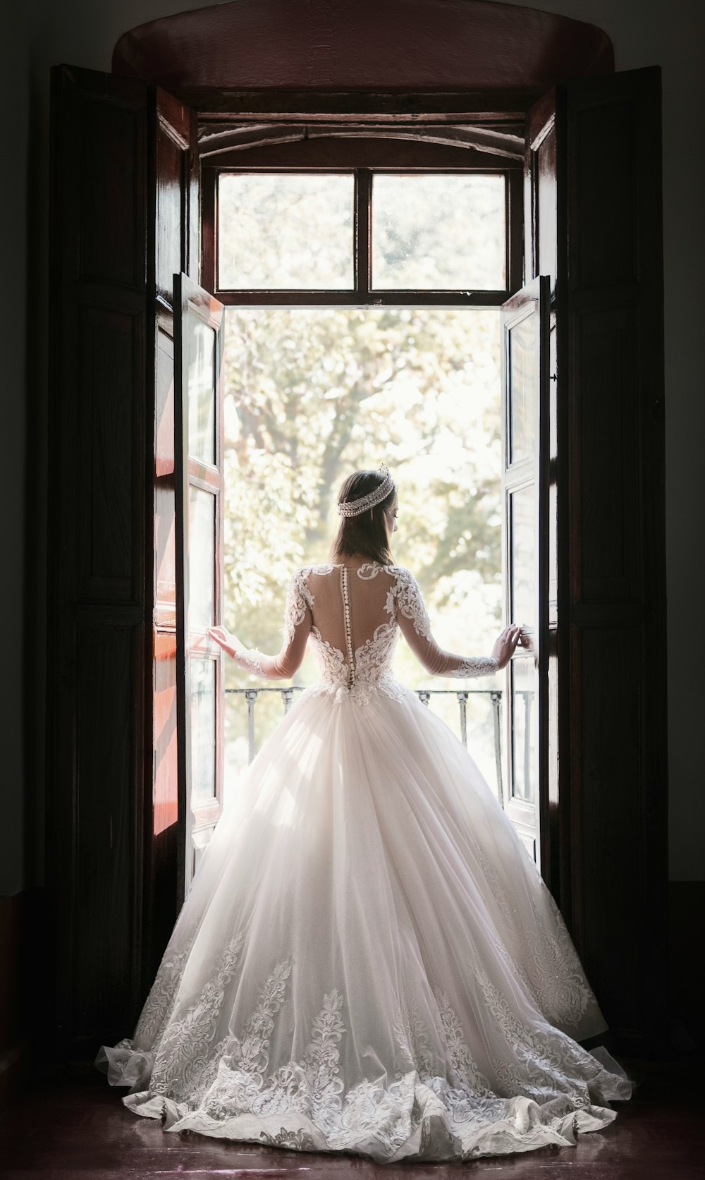woman in white wedding dress standing near window during daytime
