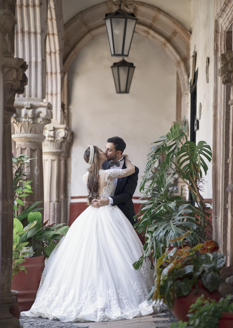 Bride in a white gown standing beside green plants