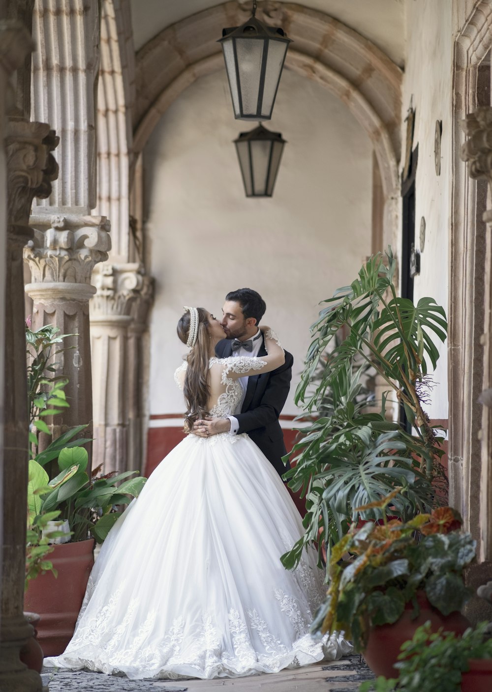 Mujer en vestido de novia blanco de pie junto a plantas verdes