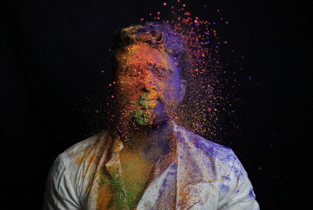 man in white shirt with green and blue powder on his face