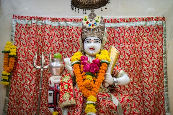woman in red and gold sari dress holding white ceramic mug
