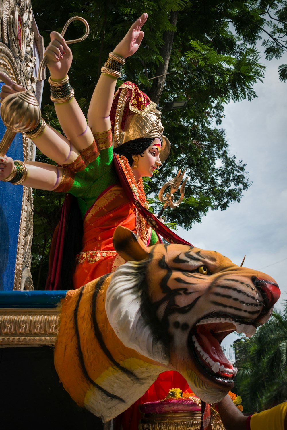 Statua della tigre vicino agli alberi verdi durante il giorno