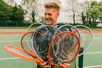 boy in blue polo shirt holding red and black tennis racket