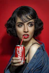 woman in blue tank top holding coca cola can