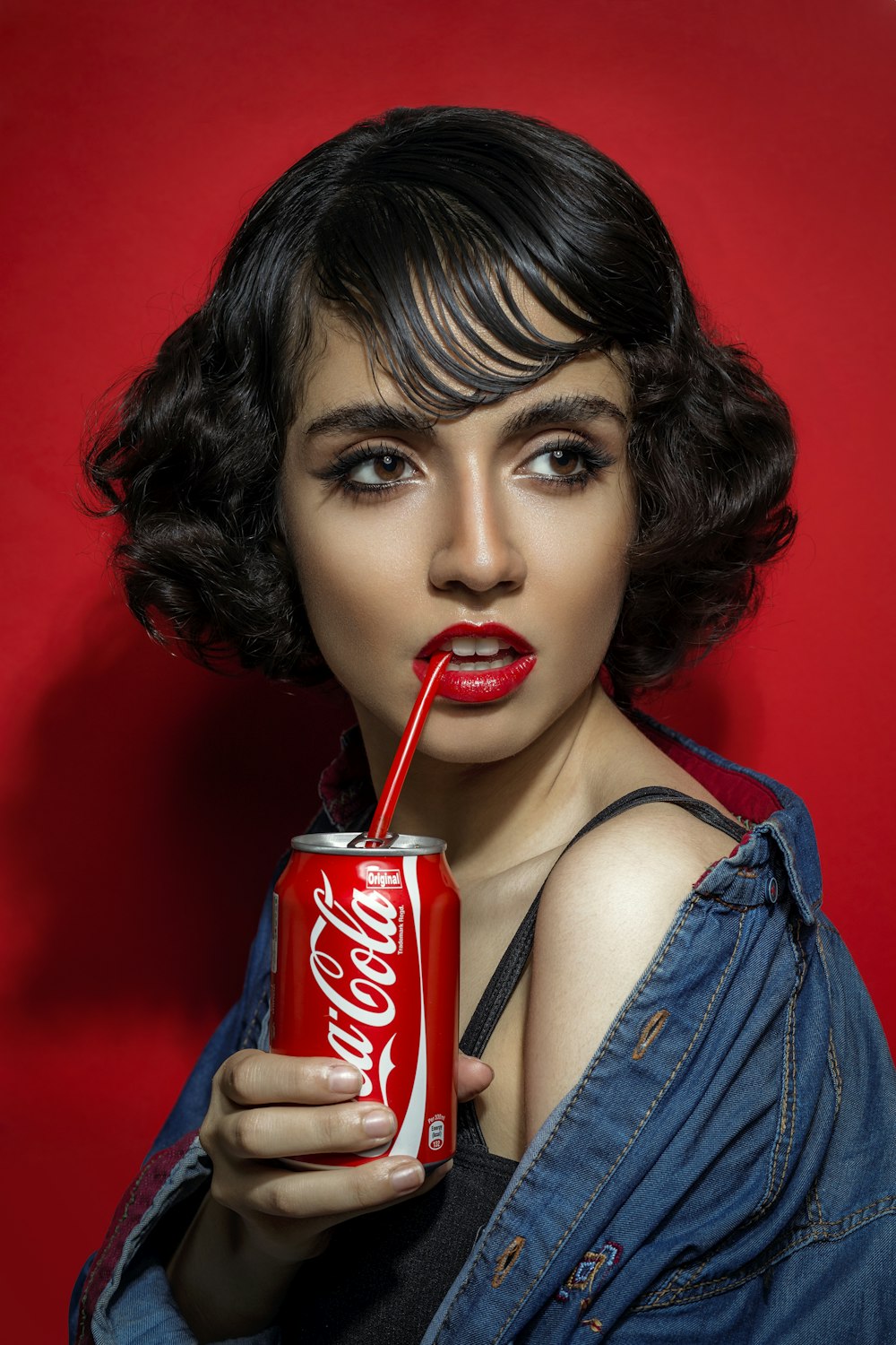 woman in blue tank top holding coca cola can