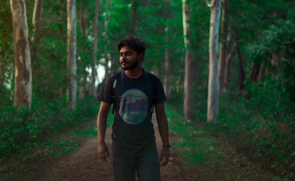 man in blue crew neck t-shirt standing on forest during daytime