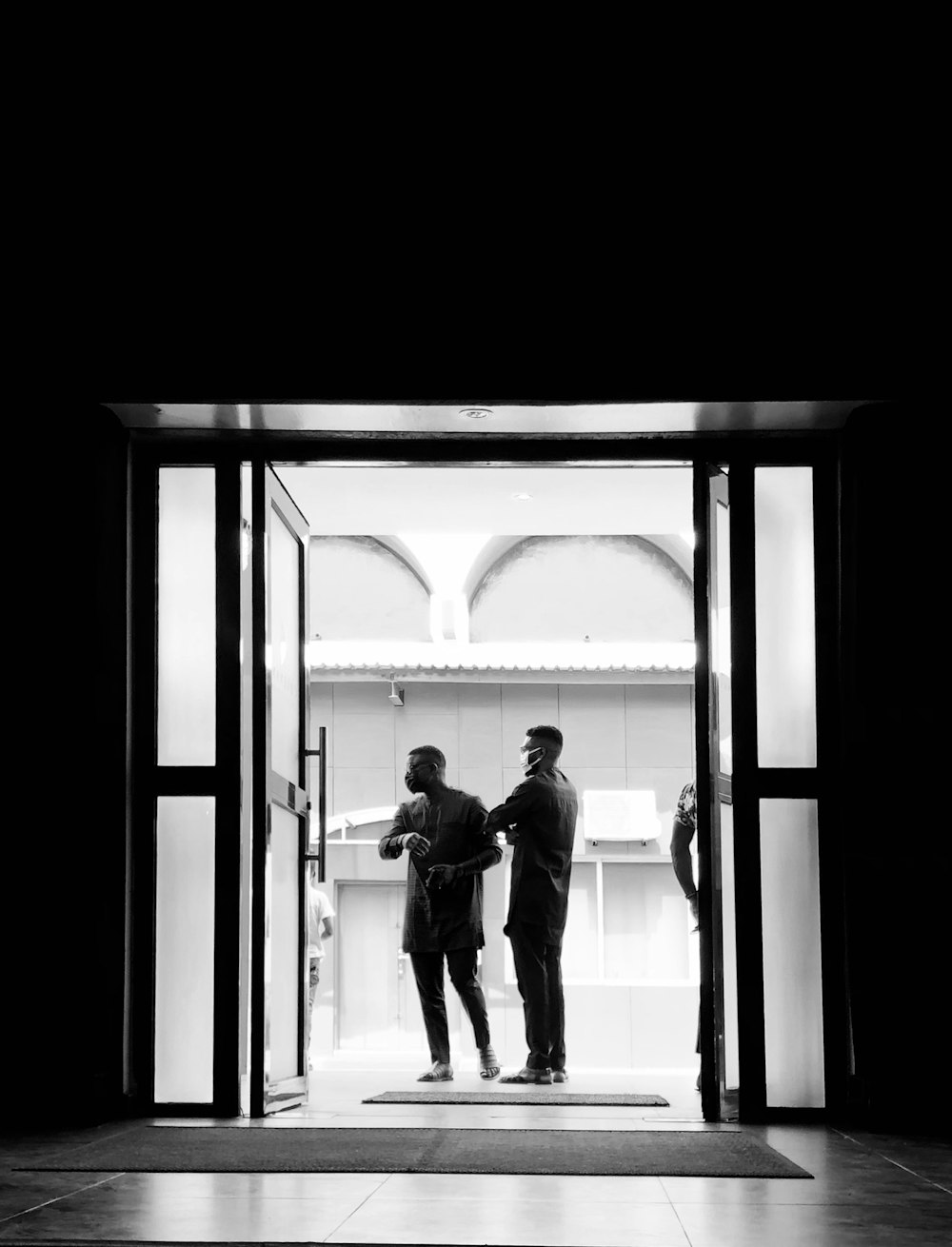 man in black jacket standing in front of glass window