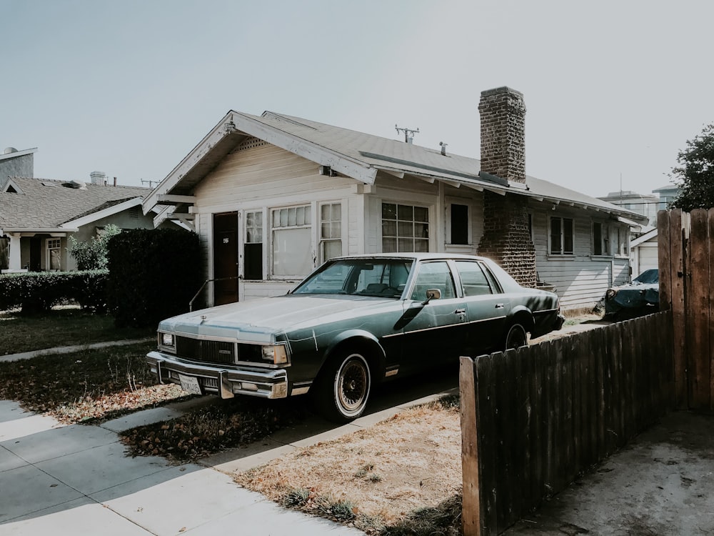 black sedan parked beside brown wooden fence