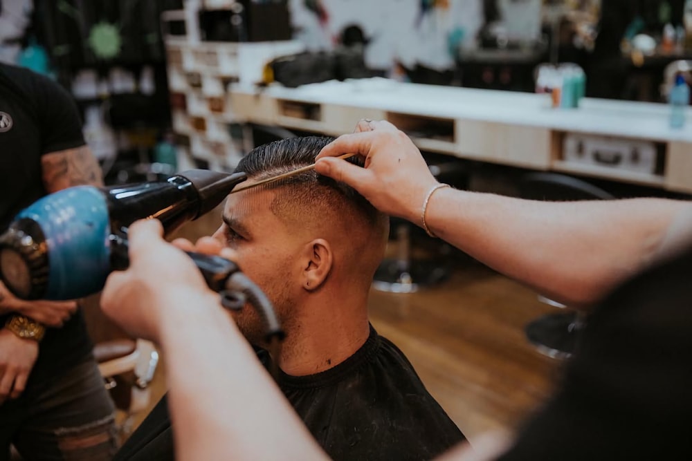 man in black t-shirt cutting hair of man