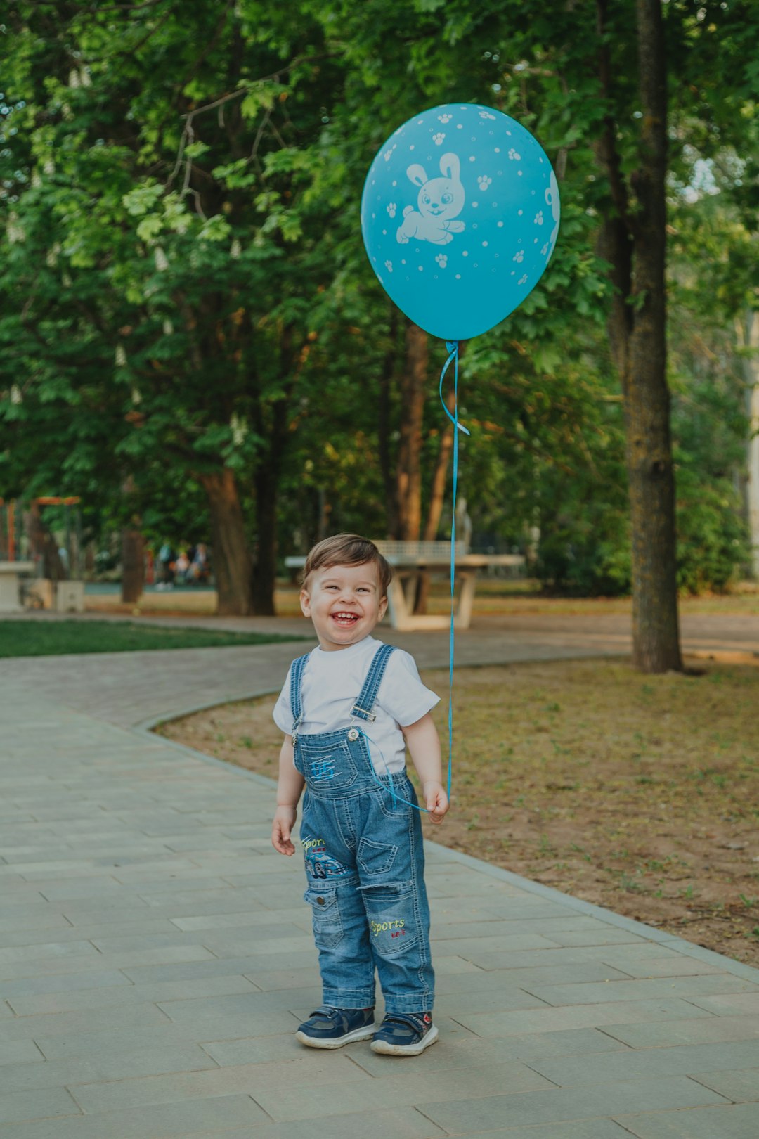 girl in white and blue tank top holding blue balloons