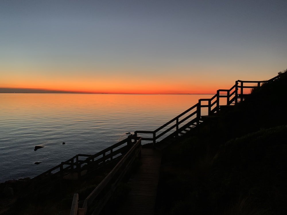 brown wooden dock on sea during sunset