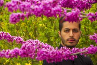 A young man working on a beautifully landscaped garden with vibrant flowers and lush greenery.
