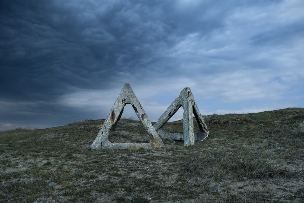 gray wooden cross on green grass field under gray cloudy sky