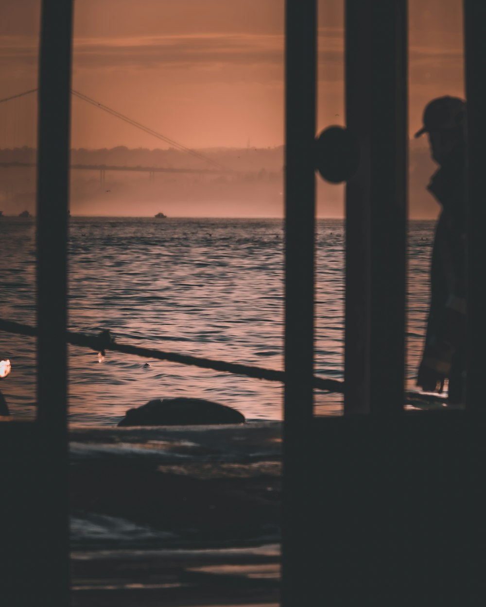 silhouette of man and woman standing beside window during sunset