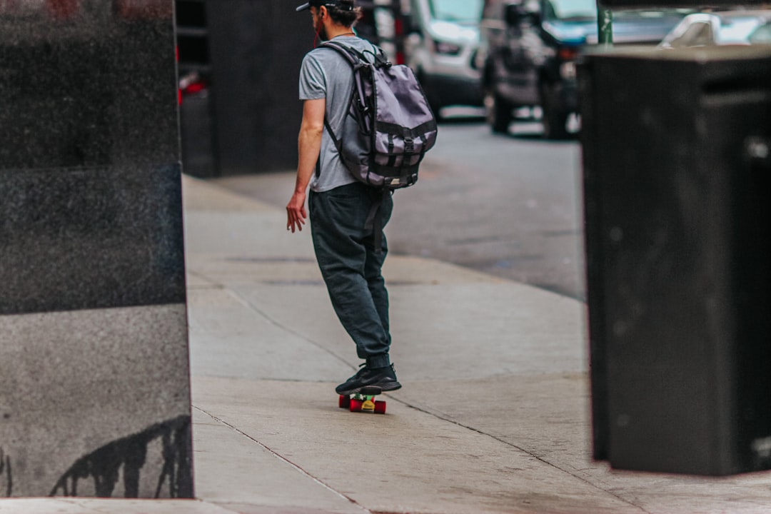 man in blue denim jacket and gray pants walking on sidewalk during daytime