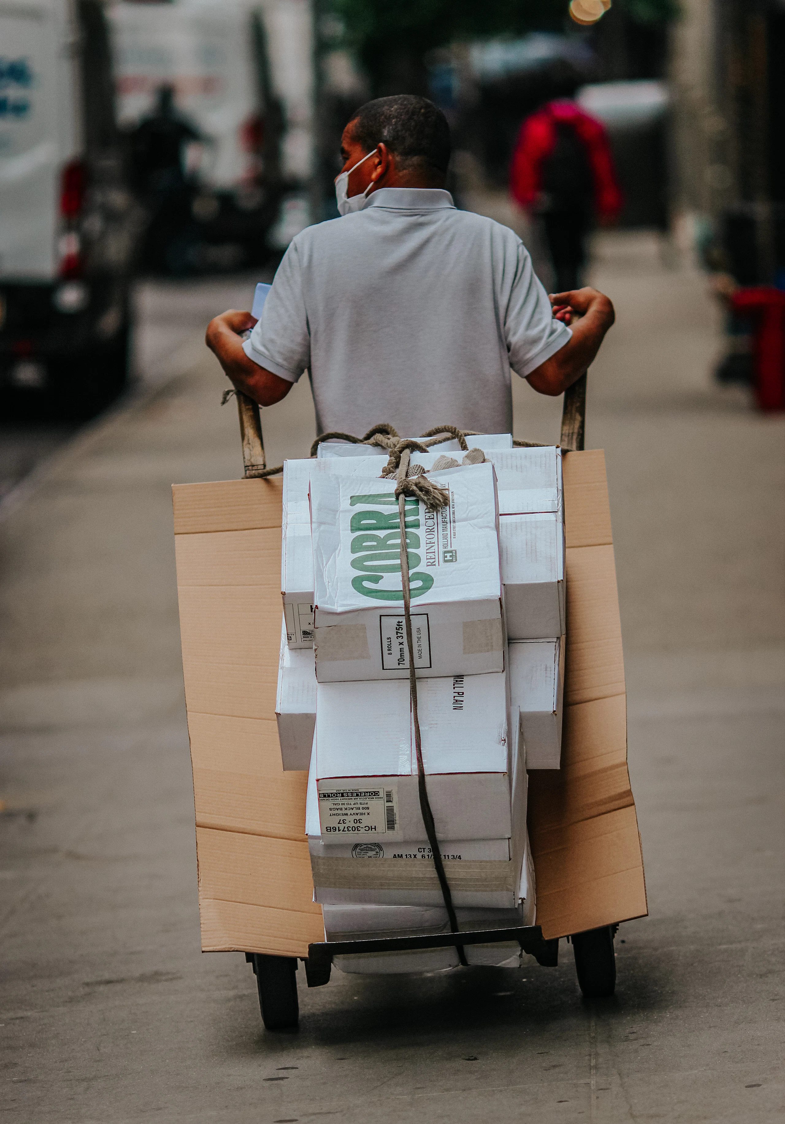 A courier moving a loaded hand truck of parcels along a delivery round