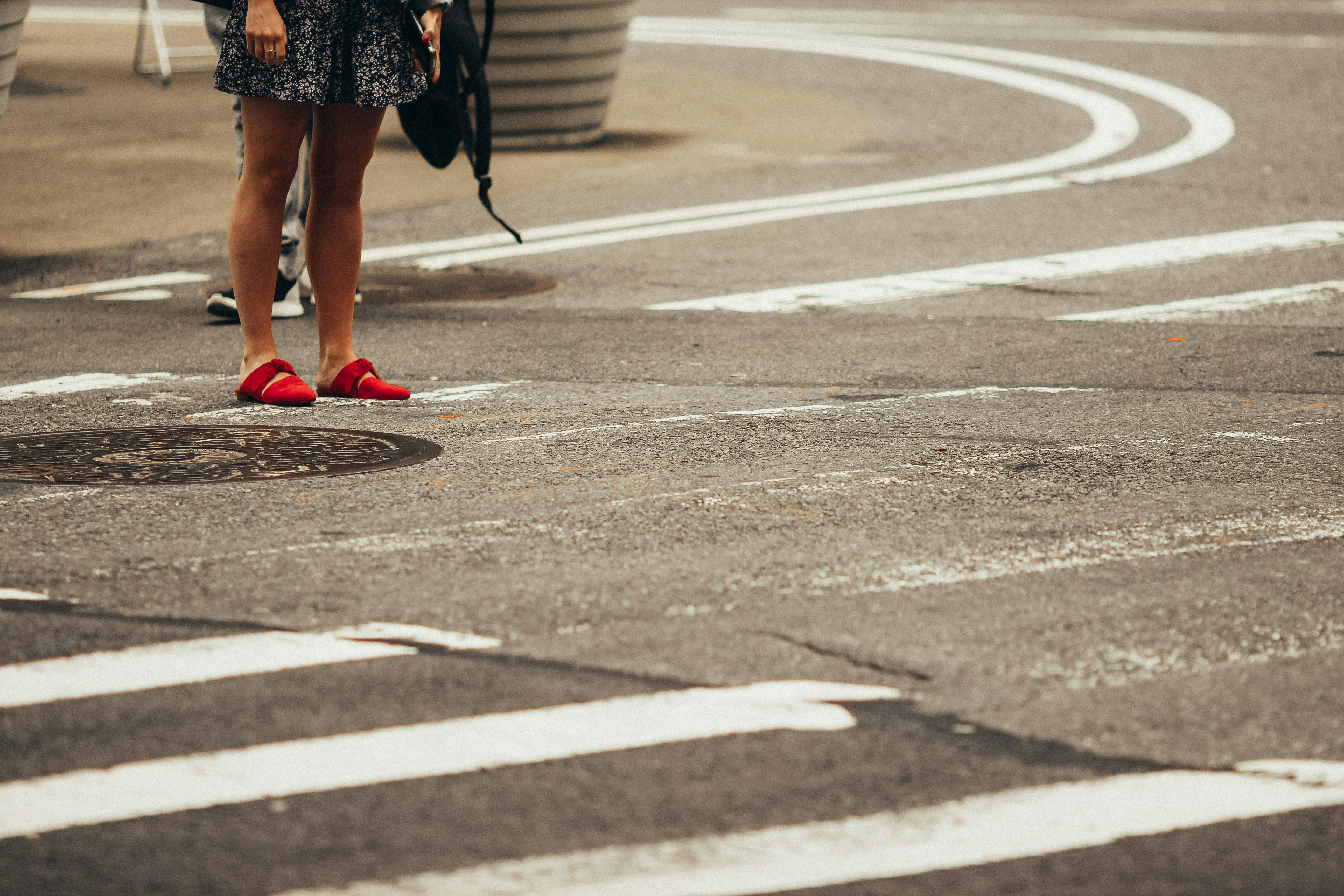 woman in black and red floral skirt walking on pedestrian lane during daytime