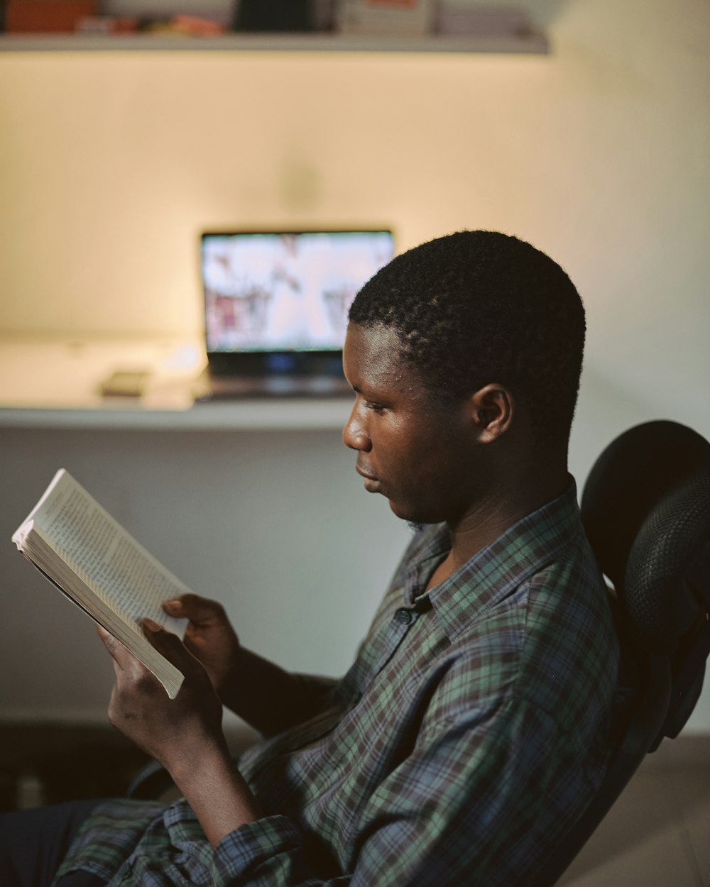 man in blue and white plaid button up shirt reading book