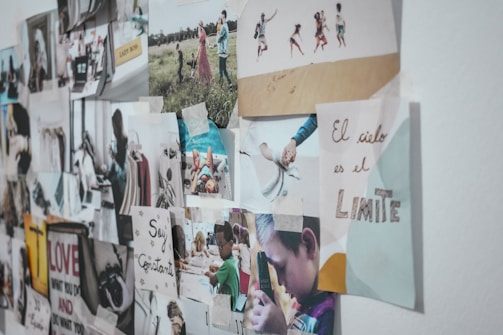 A collage of various photographs and inspirational quotes is affixed to a wall. Images include children playing, a quote in Spanish about the sky being the limit, and a mix of candid moments and motivational messages. The arrangement is slightly asymmetrical with tape visible on some edges.