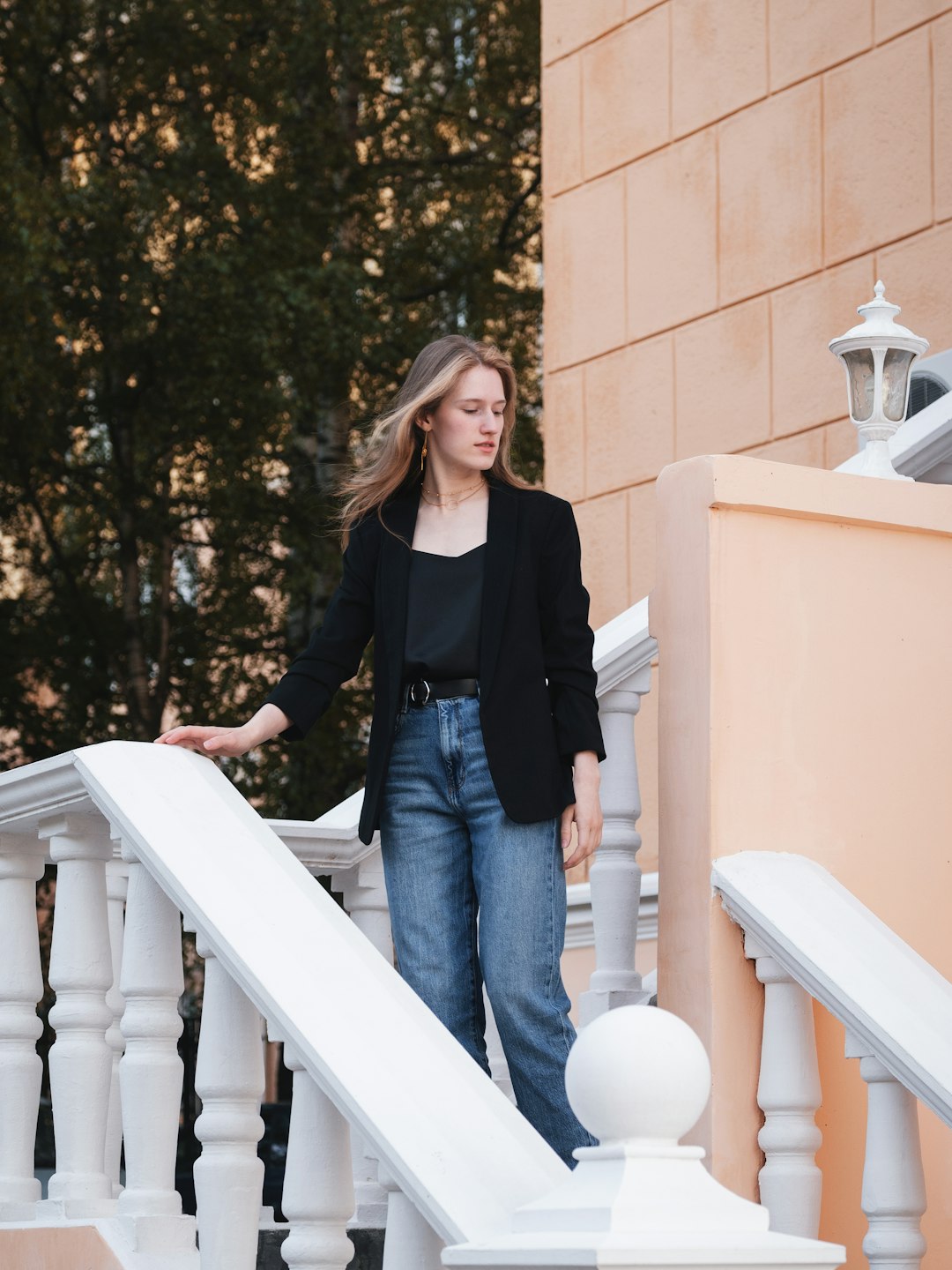 woman in black long sleeve shirt and blue denim jeans standing on white concrete staircase during