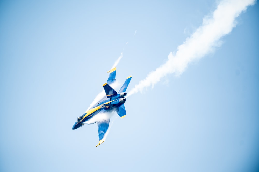 blue and white jet plane in mid air during daytime