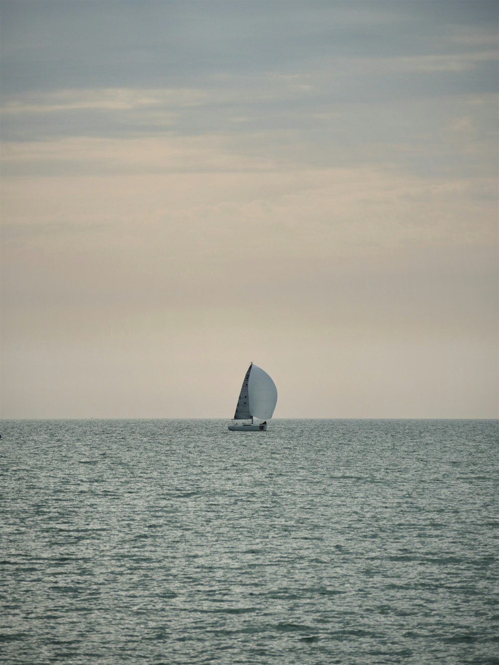 sailboat on sea under white sky during daytime