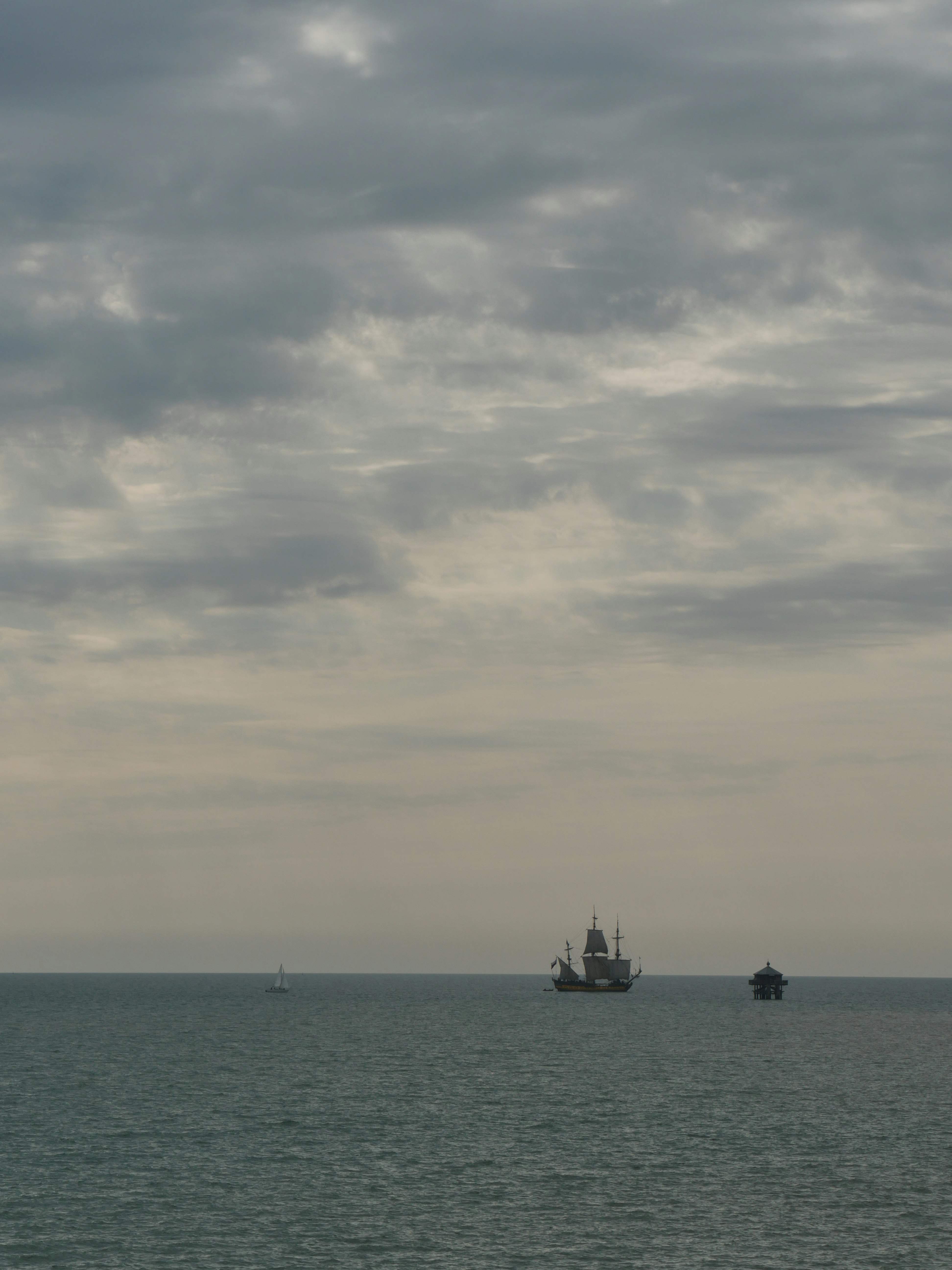 silhouette of boat on sea under cloudy sky during daytime
