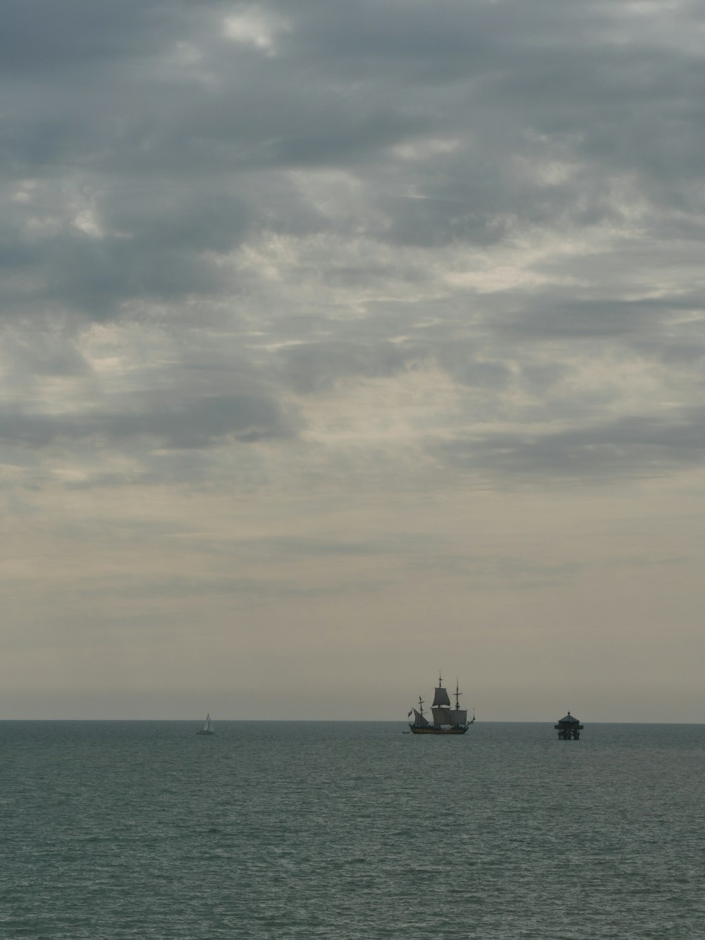 silhouette de bateau sur la mer sous ciel nuageux pendant la journée