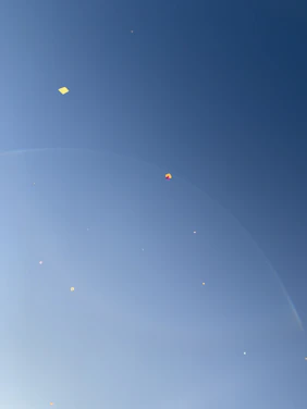 A vibrant display of colorful kites soaring against a clear blue sky.