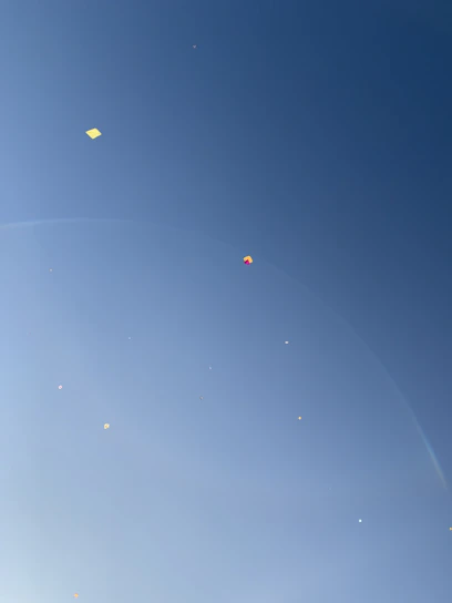 A vibrant display of colorful kites soaring against a clear blue sky.
