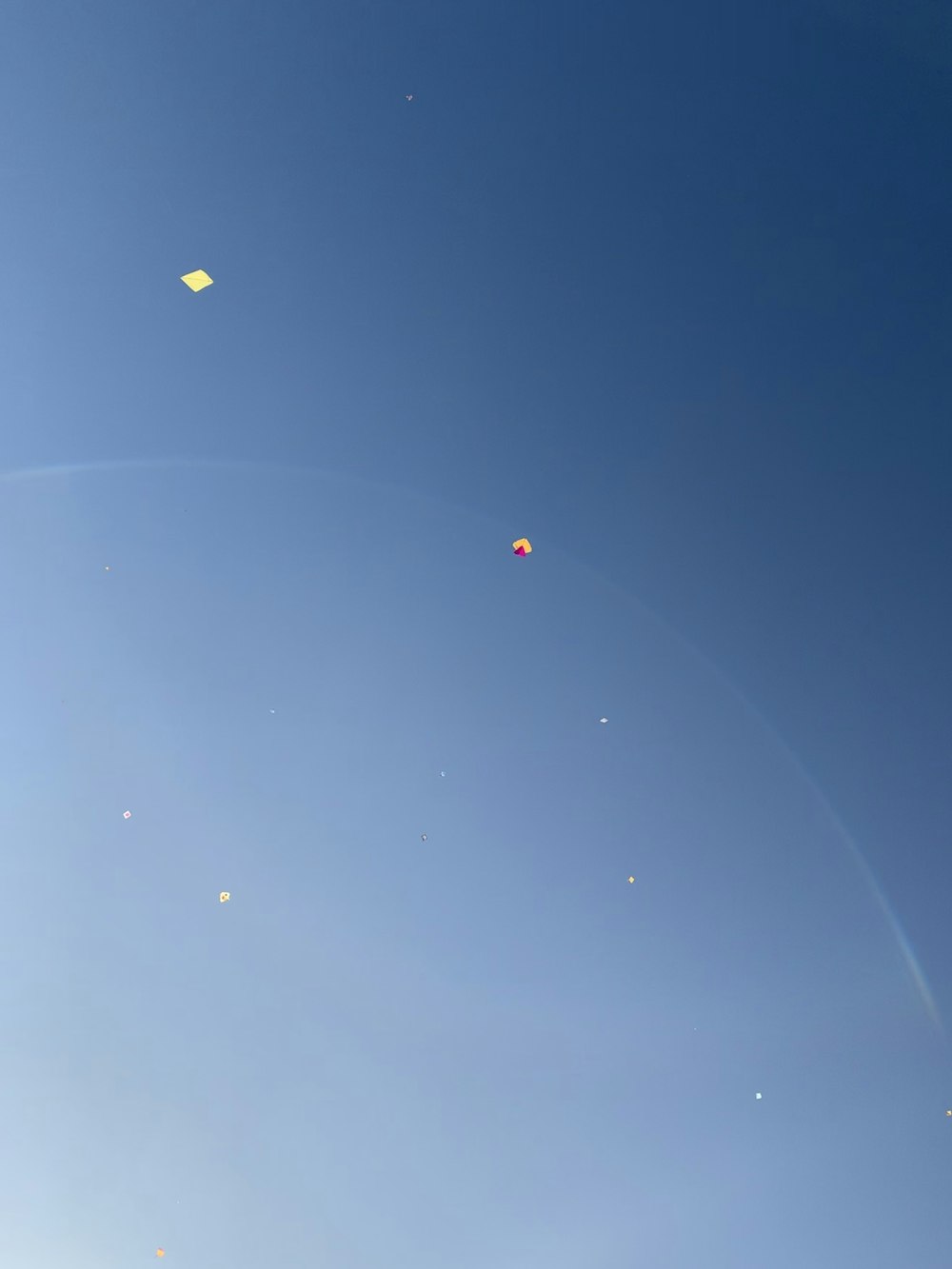 Two kites flying far in the blue sky