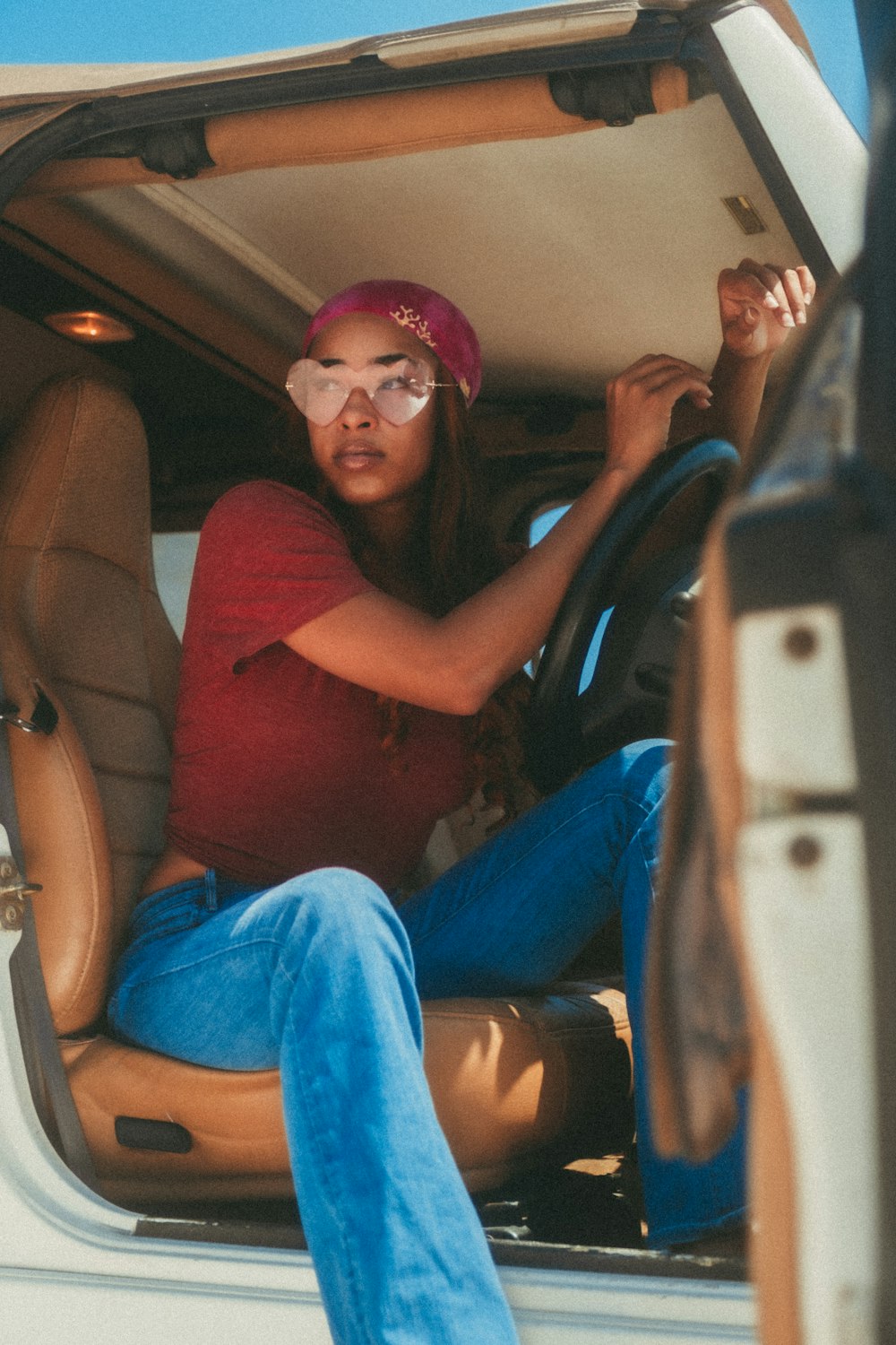 woman in brown tank top and blue denim jeans sitting on car seat