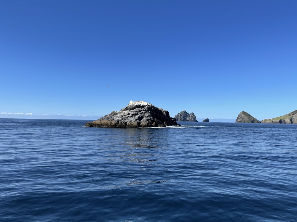 brown rock formation on sea under blue sky during daytime