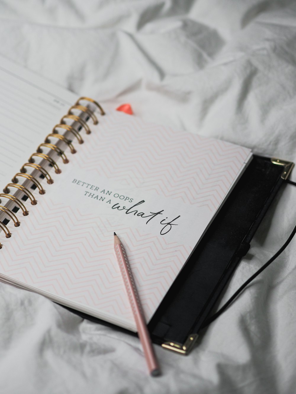 white spiral notebook with pink pen