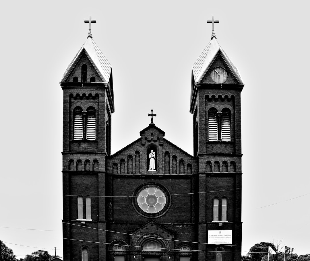 grayscale photo of church with cross on top