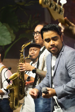 man in gray dress shirt holding saxophone