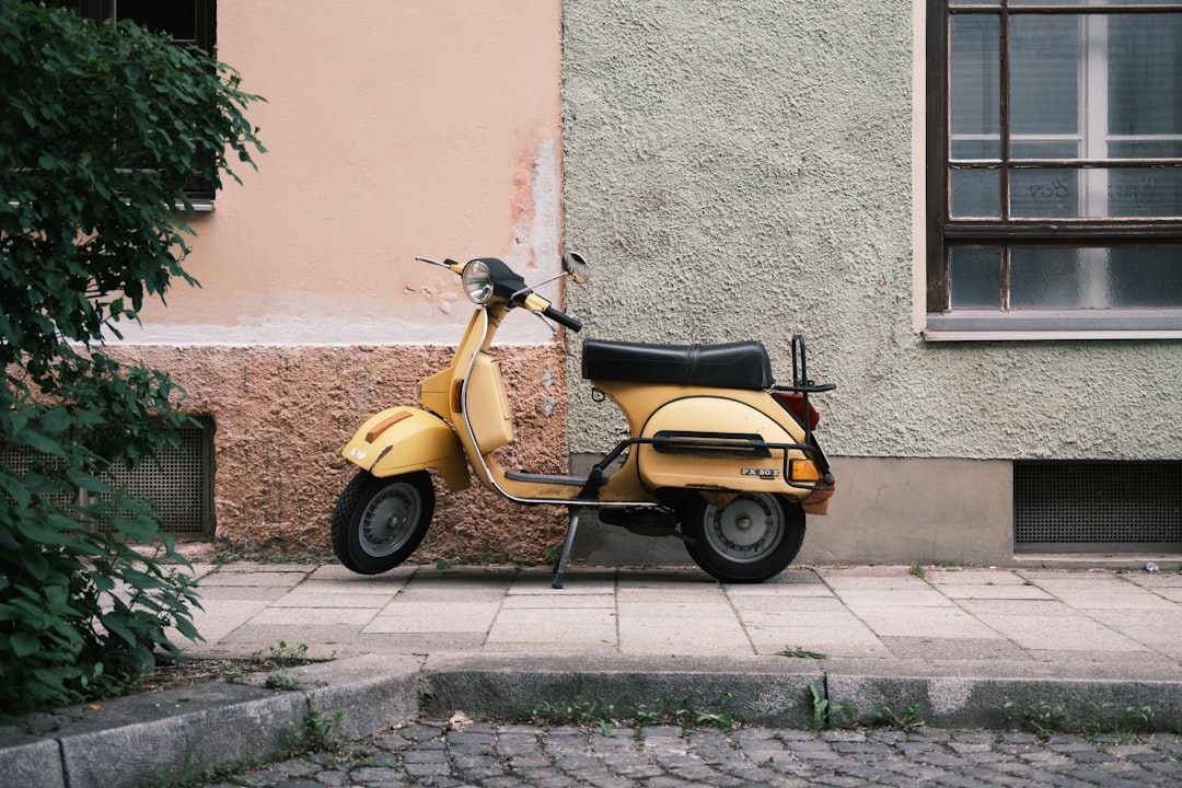 yellow and black motor scooter parked beside gray concrete wall